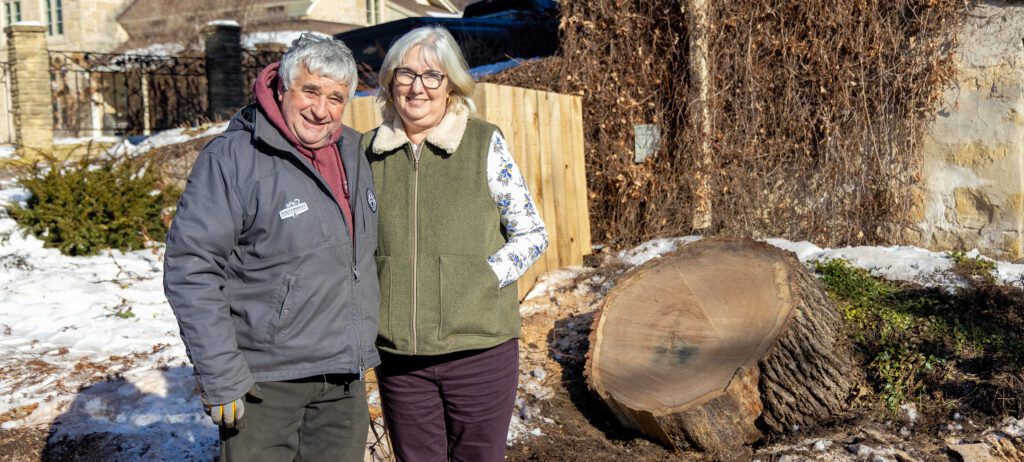 A man and woman stand next to the stump of the removed 200 year old oak tree.