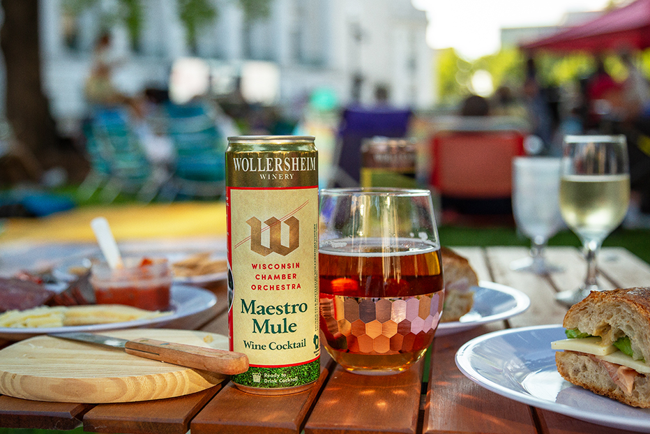 A can and glass of Maestro Mule sitting atop a travel picnic table on the Capital lawn, at Concerts on the Square in Madison, WI.
